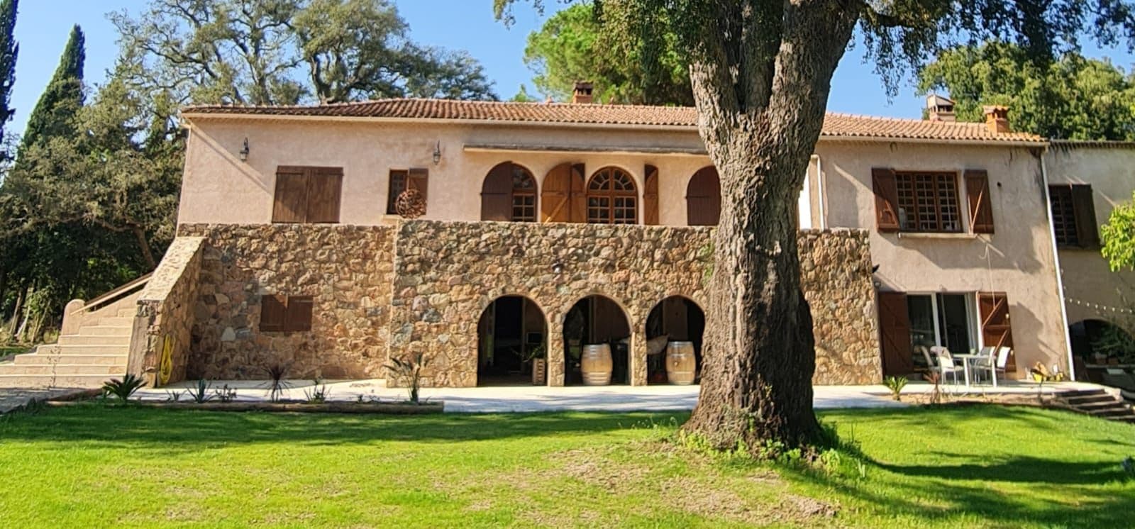 The stone house and tree-lined lawn at Domaine A FONTE